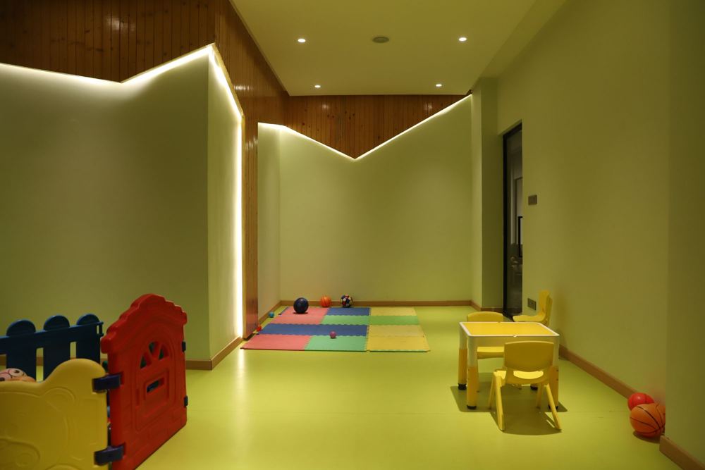 Kids' play area with green walls, soft mats and small furniture