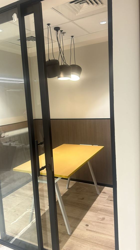 Compact meeting pod with a yellow table and cluster pendants